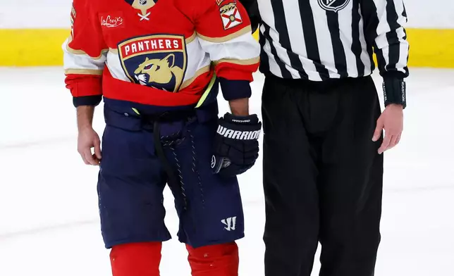 Linesman David Brisebois, right, escorts Florida Panthers left wing Brad Marchand (63) to the penalty box during the third period of an NHL hockey game against the Tampa Bay Lightning, Saturday, Dec. 27, 2025, in Sunrise, Fla. (AP Photo/Rhona Wise)