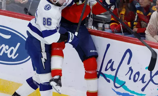 Tampa Bay Lightning right wing Nikita Kucherov (86) checks Florida Panthers defenseman Niko Mikkola (77) into the boards during the third period of an NHL hockey game, Saturday, Dec. 27, 2025, in Sunrise, Fla. (AP Photo/Rhona Wise)