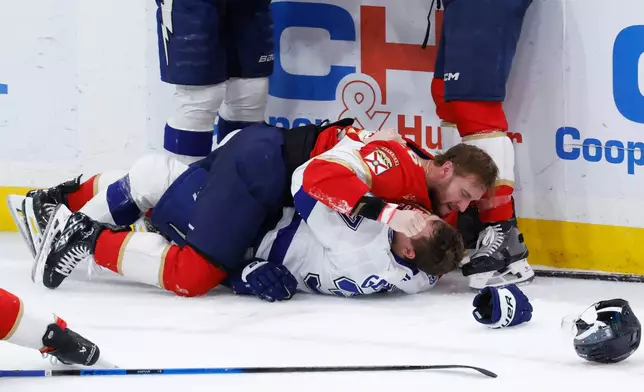 Florida Panthers defenseman Uvis Balinskis, top, and Tampa Bay Lightning center Yanni Gourde, bottom, fight during the third period of an NHL hockey game, Saturday, Dec. 27, 2025, in Sunrise, Fla. (AP Photo/Rhona Wise)