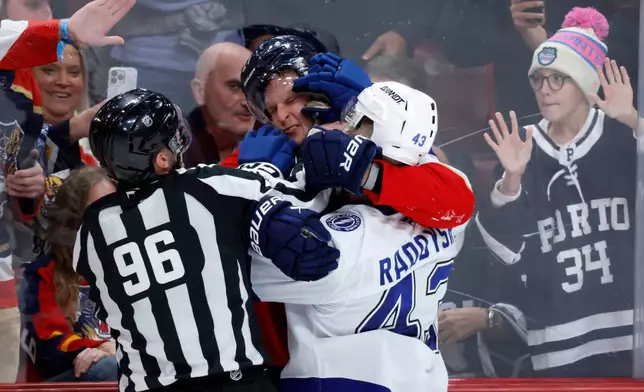 Linesman David Brisebois (96) tries to break up a fight between Florida Panthers center Eetu Luostarinen, center, and Tampa Bay Lightning defenseman Darren Raddysh (43) during the third period of an NHL hockey game, Saturday, Dec. 27, 2025, in Sunrise, Fla. (AP Photo/Rhona Wise)