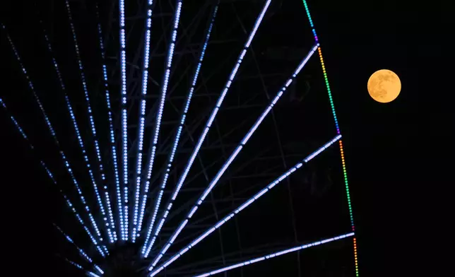 A supermoon, the last full moon of the year, rises up on the sky behind a Christmas celebrations wheel in central capital Nicosia, Cyprus, on Thursday, Dec. 4, 2025. (AP Photo/Petros Karadjias)