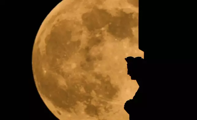The full supermoon rises beyond a spirit statue atop the Liberty Memorial tower at the National World War Museum, Thursday, Dec. 4, 2025, in Kansas City, Mo. (AP Photo/Charlie Riedel)