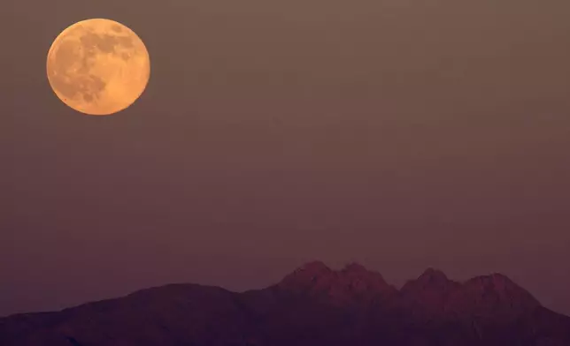 The supermoon rises over the Superstition Mountains, Thursday, Dec. 4, 2025, in Phoenix. (AP Photo/Ross D. Franklin)