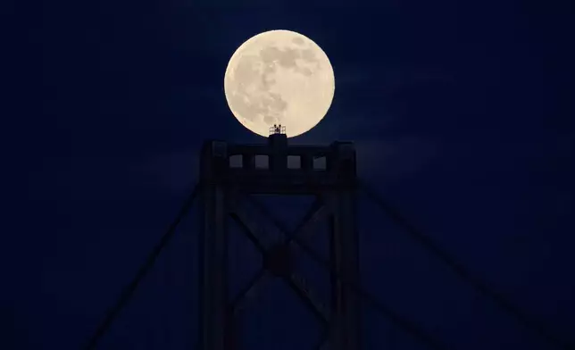 A supermoon, the last full moon of the year, rises behind the San Francisco-Oakland Bay Bridge, Thursday, Dec. 4, 2025, in San Francisco. (AP Photo/Godofredo A. Vásquez)