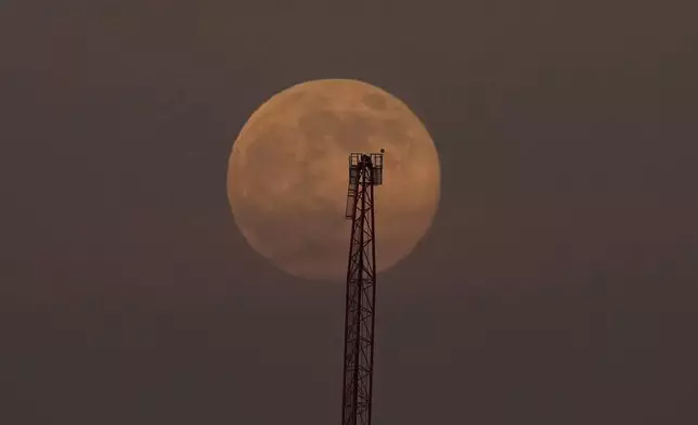 A supermoon, the last full moon of the year, rises in the sky behind a crane in San Francisco, Thursday, Dec. 4, 2025. (AP Photo/Jeff Chiu)