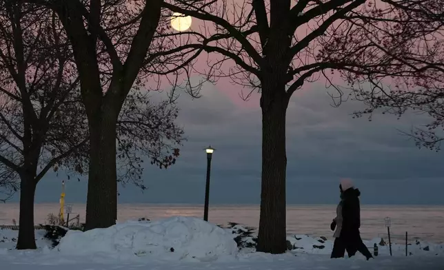 People bundle up as they take a walk during a cold weather day as the supermoon rises in Evanston, Ill., Thursday, Dec. 4, 2025. (AP Photo/Nam Y. Huh)