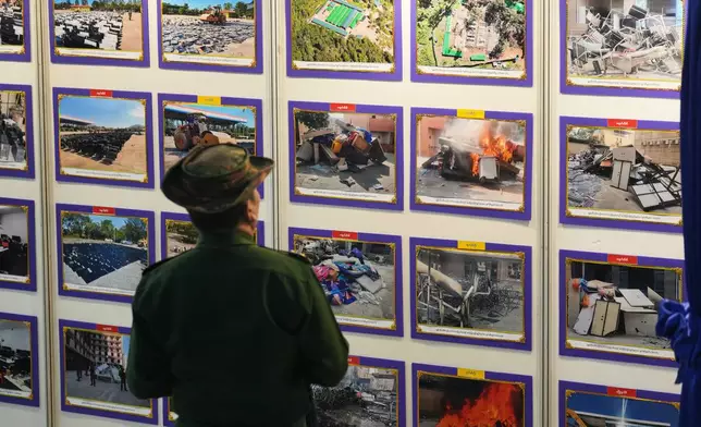 A military officer looks at photos displayed during a news conference on national level efforts to completely eliminate online scams and dismantle their networks at the root, Sunday, Dec. 14, 2025, in Yangon, Myanmar. (AP Photo/Thein Zaw)