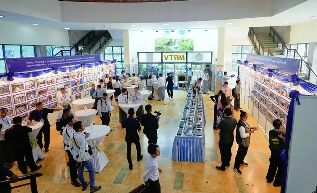 People look at seized computers from online scam centers and photos displayed during a news conference on national level efforts to completely eliminate online scams and dismantle their networks at the root, Sunday, Dec. 14, 2025, in Yangon, Myanmar. (AP Photo/Thein Zaw)
