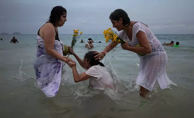 People pray on Copacabana Beach during a ceremony honoring Yemanja, the sea goddess of the Yoruba religion, in Rio de Janeiro, Monday, Dec. 29, 2025. (AP Photo/Bruna Prado)