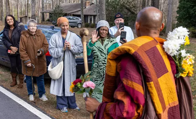 People greet Buddhist monks on a "Walk for Peace", from Texas to Washington, D.C., on Veterans Parkway in Fayetteville, Ga., on Monday, Dec. 29, 2025. (Arvin Temkar/Atlanta Journal-Constitution via AP)