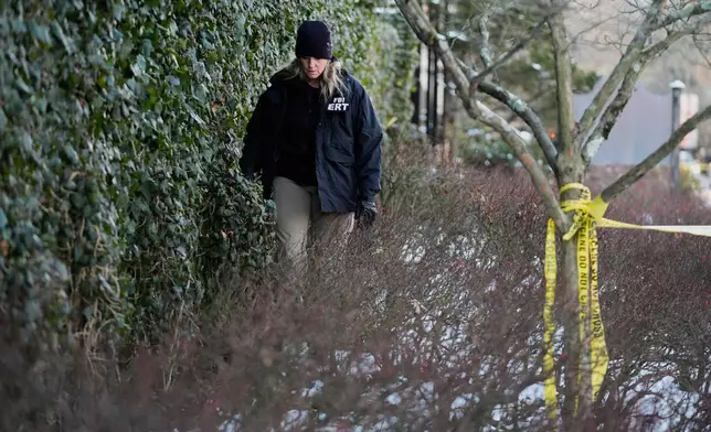 A member of the FBI Evidence Response Team searches for evidence near an ivy-covered wall following the shooting at Brown University, Monday, Dec. 15, 2025, in Providence, R.I. (AP Photo/Robert F. Bukaty)
