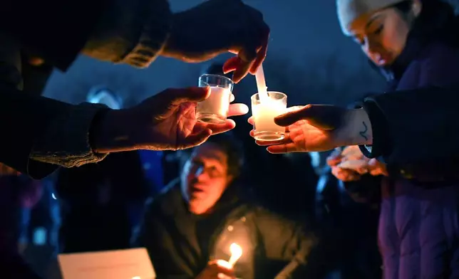 People light candles at the beginning of a vigil, Sunday, Dec. 14, 2025, in Providence, R.I., for those injured or killed during the Saturday shooting on the campus of Brown University. (AP Photo/Steven Senne)