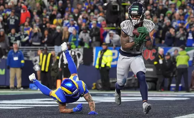 Seattle Seahawks wide receiver Jaxon Smith-Njigba (11) scores a touchdown during overtime in an NFL football game against the Los Angeles Rams, Thursday, Dec. 18, 2025, in Seattle. (AP Photo/Lindsey Wasson)