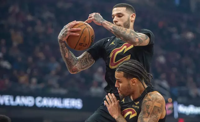 Cleveland Cavaliers' Lonzo Ball, top, grabs a rebound over Jaylon Tyson, bottom, during the first half of an NBA basketball game in Cleveland, Sunday, Dec. 14, 2025. (AP Photo/Phil Long)
