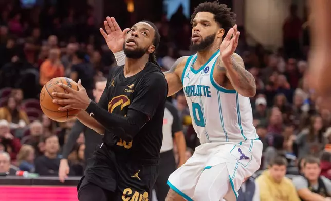 Cleveland Cavaliers' Darius Garland, left, drives as Charlotte Hornets' Miles Bridges (0) defends during the second half of an NBA basketball game in Cleveland, Sunday, Dec. 14, 2025. (AP Photo/Phil Long)