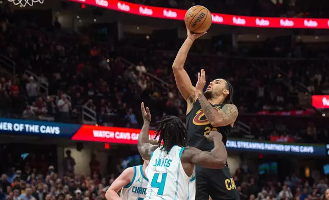 Cleveland Cavaliers' Jaylon Tyson, top, goes up to shoot over Charlotte Hornets' Sion James (4) and Kon Knueppel, back left, during the second half of an NBA basketball game in Cleveland, Sunday, Dec. 14, 2025. (AP Photo/Phil Long)