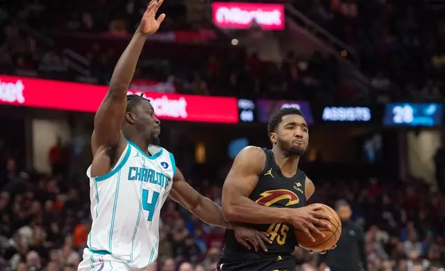 Cleveland Cavaliers' Donovan Mitchell (45) keeps the ball away from Charlotte Hornets' Sion James (4) during the second half of an NBA basketball game in Cleveland, Sunday, Dec. 14, 2025. (AP Photo/Phil Long)