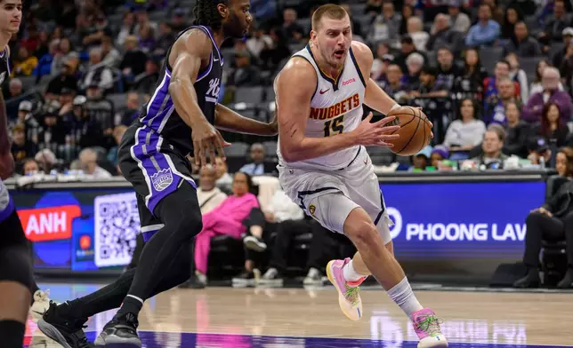 Denver Nuggets center Nikola Jokic (15) drives past Sacramento Kings forward Precious Achiuwa during the first half of an NBA basketball game in Sacramento, Calif., Thursday, Dec. 11, 2025. (AP Photo/Randall Benton)