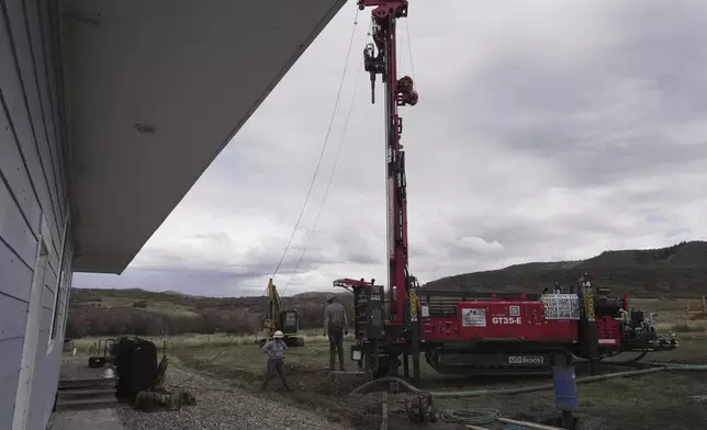 The Cooper family prepares to drill a hole for a geothermal heat pump installation Thursday, Oct. 9, 2025, in Hamilton, Colo. (AP Photo/Brittany Peterson)
