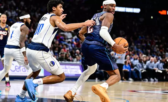 Oklahoma City Thunder guard Shai Gilgeous-Alexander, right, drives against Dallas Mavericks guard Max Christie (00) during the second half of an NBA basketball game, Friday, Dec. 5, 2025, in Oklahoma City. (AP Photo/Gerald Leong)