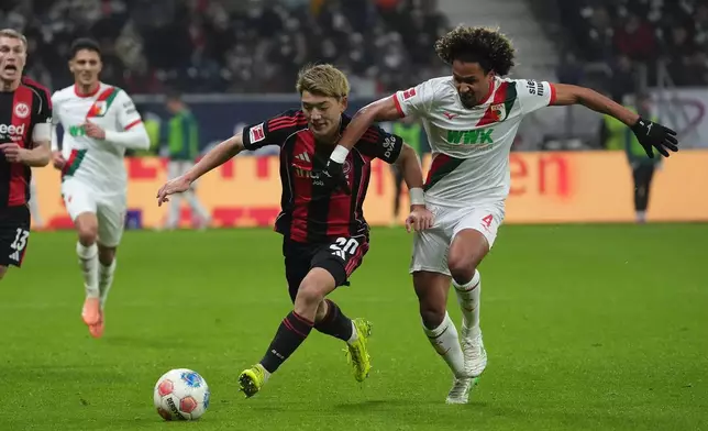 Frankfurt's Ritsu Doan, left, and Augsburg's Han-Noah Massengo, right, challenge for the ball during the German Bundesliga soccer match between Eintracht Frankfurt and FC Augsburg in Frankfurt, Germany, Saturday, Dec. 13, 2025. (Marc Schueler/dpa via AP)