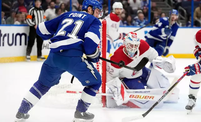 Tampa Bay Lightning center Brayden Point (21) plays the puck in front of Montréal Canadiens goaltender Jacob Fowler (32) during the second period of an NHL hockey game Sunday, Dec. 28, 2025, in Tampa, Fla. (AP Photo/Chris O'Meara)