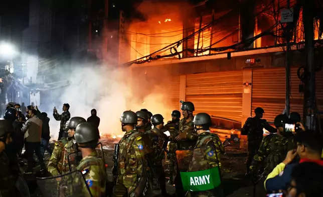 Bangladesh army stands guard at the premises of the Prothom Alo daily newspaper after angry protesters set it on fire after news reached the country from Singapore of the death of a prominent activist Sharif Osman Hadi, in Dhaka, Bangladesh, Friday, Dec. 19, 2025. (AP Photo/Mahmud Hossain Opu)