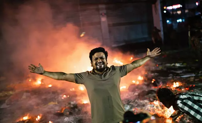 A protester reacts to the camera near the premises of the Prothom Alo daily newspaper which was set on fire by angry protesters after news reached the country from Singapore of the death of a prominent activist Sharif Osman Hadi, in Dhaka, Bangladesh, Friday, Dec. 19, 2025. (AP Photo/Mahmud Hossain Opu)