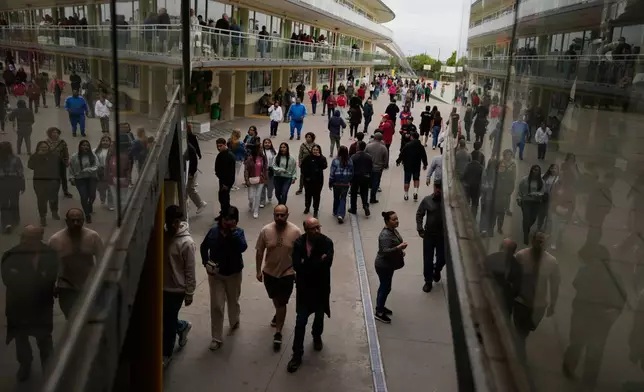 Voters arrive to a polling stating during the presidential runoff election in Santiago, Chile, Sunday, Dec. 14, 2025. (AP Photo/Matias Delacroix)