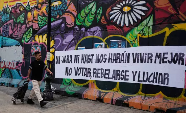A campaign banner reads in Spanish "Neither Jara nor Kast will make our lives better, don't vote, rebel and fight" ahead of the presidential runoff election in Santiago, Chile, Friday, Dec. 12, 2025. (AP Photo/Natacha Pisarenko)