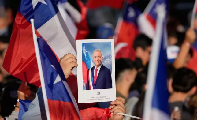 Supporters hold a portrait of Jose Antonio Kast, presidential candidate of the opposition Republican Party, after results show hime leading in the presidential runoff election in Santiago, Chile, Sunday, Dec. 14, 2025.(AP Photo/Matias Delacroix)