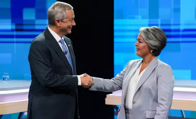 Presidential candidates Jose Antonio Kast of the Republican Party and Jeannette Jara of the Unity for Chile coalition shake hands during a debate ahead of runoff elections in Santiago, Chile, Tuesday, Dec. 9, 2025. (AP Photo/Esteban Felix)