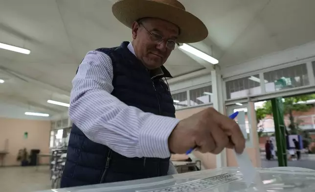 A voter casts his ballot during the presidential runoff election in Santiago, Chile, Sunday, Dec. 14, 2025. (AP Photo/Esteban Felix)