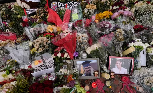Photos of Brown University shooting victims Mukhammad Aziz Umurzokov, left, and Ella Cook, are seen amongst flowers at a makeshift memorial at the school's Van Wickle Gate, Wednesday, Dec. 17, 2025, in Providence, R.I. (AP Photo/Robert F. Bukaty)