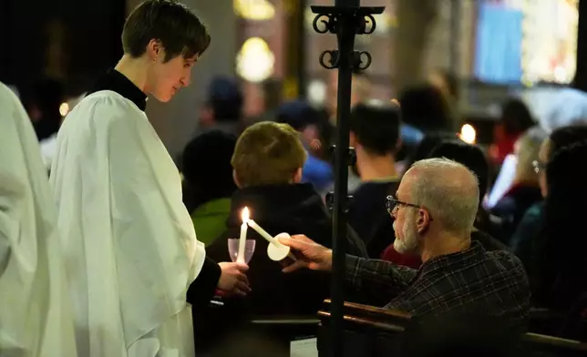 Participants light candles at St. Stephen's Church during a community service for the victims of the Brown University shooting, Tuesday, Dec. 16, 2025. (AP Photo/Robert F. Bukaty)