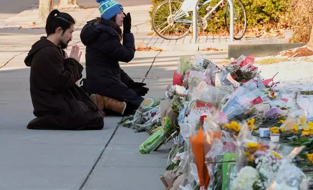 Visitors kneel at a makeshift memorial for the shooting victims outside the Engineering Research Center at Brown University, Tuesday, Dec. 16, 2025, in Providence, R.I.(AP Photo/Robert F. Bukaty)