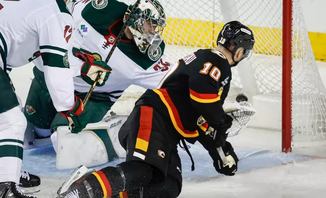 Minnesota Wild goalie Filip Gustavsson, left, is scored on by Calgary Flames' Jonathan Huberdeau during second period NHL hockey action in Calgary on Thursday, Dec. 4, 2025. (Jeff McIntosh/The Canadian Press via AP)