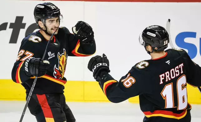 Calgary Flames' Matt Coronato, left, celebrates his goal with teammate Morgan Frost during third period NHL hockey action against the Minnesota Wild in Calgary on Thursday, Dec. 4, 2025. (Jeff McIntosh/The Canadian Press via AP)