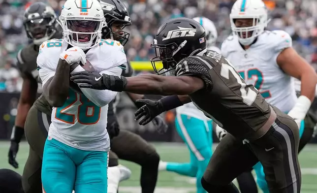 Miami Dolphins running back De'Von Achane (28) carries the ball for a touchdown against New York Jets cornerback Brandon Stephens (21) during the first quarter of an NFL football game, Sunday, Dec. 7, 2025, in East Rutherford, N.J. (AP Photo/Yuki Iwamura)