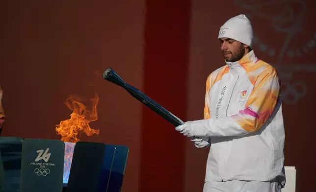 Italian swimmer Gregorio Paltrinieri lights the 2026 Milan Cortina Winter Olympics torch in Rome as it begins its journey through Italy, Saturday, Dec. 6, 2025, a journey that will conclude in Milan in February 2026. (AP Photo/Andrew Medichini)