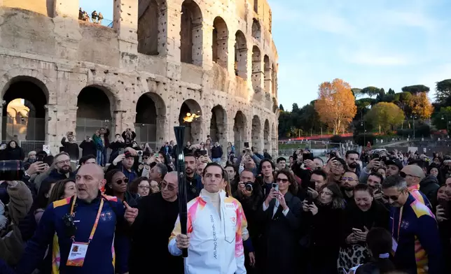 Italian pope singer Achille Lauro carries the 2026 Milan Cortina Winter Olympics torch in front of the Colosseum in Rome along its journey through Italy, Saturday, Dec. 6, 2025, a journey that will conclude in Milan in February 2026. (AP Photo/Gregorio Borgia)