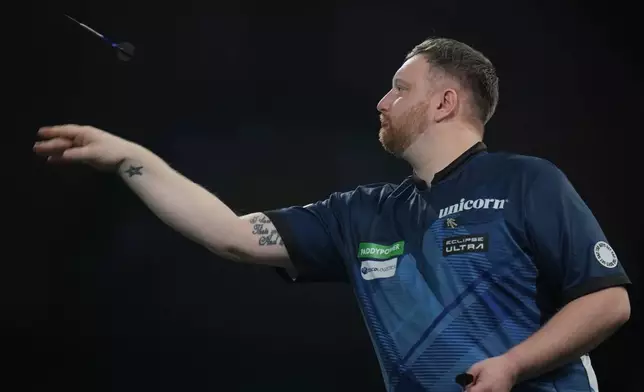 Cameron Menzies of Scotland throws a dart as he takes part in a round one match at the World Darts Championships, at Alexandra Palace in London, Monday, Dec. 15, 2025. (AP Photo/Kin Cheung)