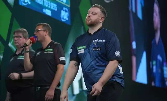 Cameron Menzies of Scotland reacts as he takes part in a round one match at the World Darts Championships, at Alexandra Palace in London, Monday, Dec. 15, 2025. (AP Photo/Kin Cheung)