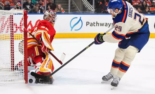 Calgary Flames goalie Dustin Wolf (32) stops a shot by Edmonton Oilers' Leon Draisaitl (29) during second period NHL action in Edmonton, Alberta, Tuesday, Dec. 23, 2025. (Amber Bracken/The Canadian Press via AP)