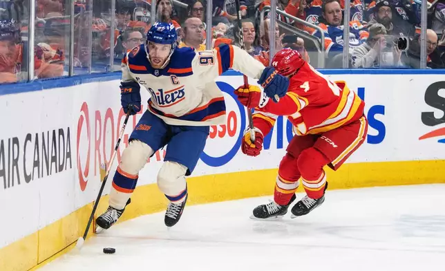 Calgary Flames' Joel Hanley (44) chases Edmonton Oilers' Connor McDavid (97) during second period NHL action in Edmonton, Alberta, Tuesday, Dec. 23, 2025. (Amber Bracken/The Canadian Press via AP)