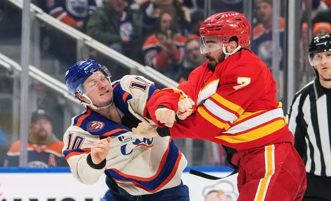Calgary Flames' Kevin Bahl (7) fights Edmonton Oilers' Trent Frederic (10) during second period NHL action in Edmonton, Alberta, Tuesday, Dec. 23, 2025. (Amber Bracken/The Canadian Press via AP)