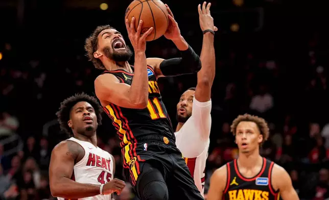 Atlanta Hawks guard Trae Young (11) shoots past Miami Heat guard Davion Mitchell (45) during the first half of an NBA basketball game, Friday, Dec. 26, 2025, in Atlanta. (AP Photo/Mike Stewart)