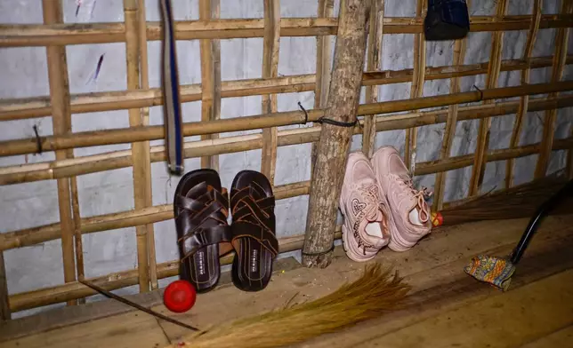 Brown sandals of 13-year-old Mohammed are propped against the wall, alongside sparkly pink sneakers belonging to his sister, inside their shelter in the Rohingya refugee camp in Cox's Bazar, Bangladesh, Saturday, Nov. 22, 2025. (AP Photo/Mahmud Hossain Opu)