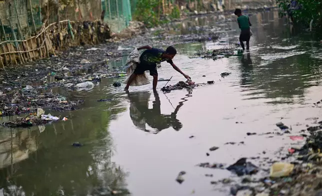 Thirteen-year-old Rohingya refugee Rahamot Ullah collects plastic waste from a drainage canal inside the Rohingya refugee camp in Cox's Bazar, Bangladesh, Saturday, Nov. 22, 2025. (AP Photo/Mahmud Hossain Opu)