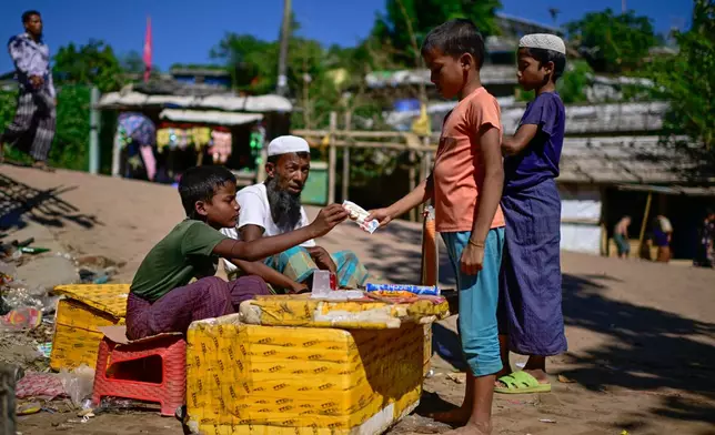 Ten-year-old Rohingya refugee Mohammed Arfan, left, sells snacks inside the Rohingya refugee camp in Cox's Bazar, Bangladesh, Friday, Nov. 21, 2025. (AP Photo/Mahmud Hossain Opu)